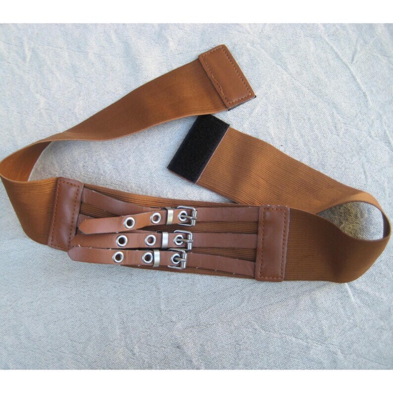 May include: A brown elastic waist belt with three rows of silver buckles and eyelets. The belt has brown leather accents and a velcro closure. The belt is designed to cinch the waist.