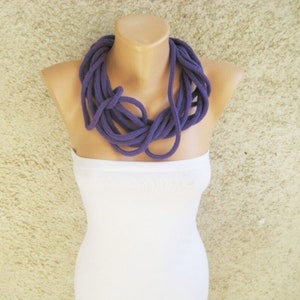 Puede incluir: Un collar grueso de cuerda de color morado. El collar está hecho de varios hilos de cuerda que están trenzados juntos. El collar se lleva en un maniquí.