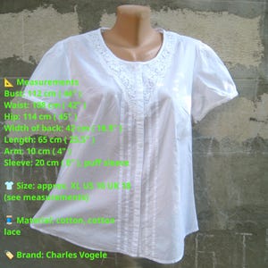 May include: White cotton blouse with a lace-trimmed neckline and short puff sleeves. The blouse has vertical pleats down the front and measures 44 inches at the bust and 25.5 inches in length.