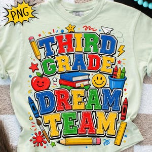 Op de afbeelding: Een lichtgroen t-shirt met een kleurrijke afbeelding en de tekst "THIRD GRADE DREAM TEAM" in dikke blokletters. Het ontwerp bevat illustraties van een potlood, een rode appel, een stapel boeken, een smiley, kleurpotloden en een liniaal.