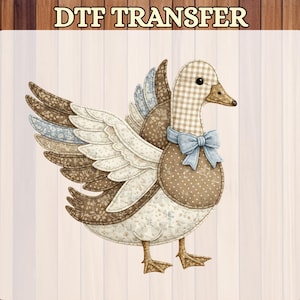 May include: DTF TRANSFER image of a duck with patchwork wings and body. The duck has a checkered head and a blue bow tie. The text "Ready to Press" is at the bottom. The background is a light beige color.