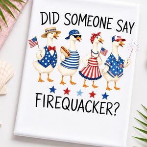 May include: White towel with a patriotic design featuring four geese dressed in red, white, and blue outfits. The text "DID SOMEONE SAY FIREQUACKER?" is printed on the towel. The geese are holding American flags and a sparkler.