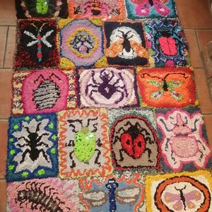 May include: A colorful, handmade rug featuring a patchwork design of various insects and butterflies. Each square showcases a different bug, including a dragonfly, ladybug, and spider, in vibrant colors like pink, green, and blue. The rug is made of textured yarn.