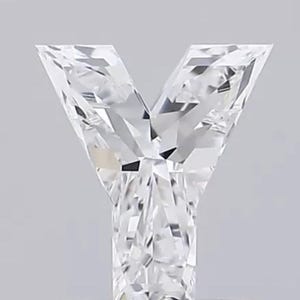 May include: A clear, faceted diamond in the shape of the letter "Y". The gemstone has sharp angles and a brilliant, reflective surface. The letter is set against a light gray background, showcasing its clarity and cut.