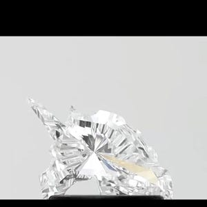 May include: A clear, faceted gemstone with sharp angles and a brilliant, reflective surface. The gem is set against a light background, showcasing its clarity and sparkle. The overall shape is irregular, with multiple facets.