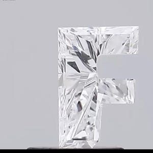 May include: A clear, faceted gemstone shaped like the letter "F". The gem has a square cut with multiple facets, creating a sparkling effect. The background is a solid, light gray.