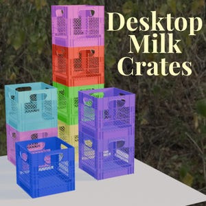 Puede incluir: Una colección de cajas de leche de plástico de colores en varios tonos de azul, rosa, morado, verde, naranja y amarillo. Las cajas están apiladas y dispuestas sobre una superficie blanca, con el texto "Desktop Milk Crates" en el fondo.