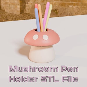 May include: A whimsical mushroom-shaped pen holder in soft pink and white, with two white circular accents on the cap. The holder contains several colorful pens in shades of blue, orange, pink, and yellow. The text "Mushroom Pen Holder STL File" is displayed below.