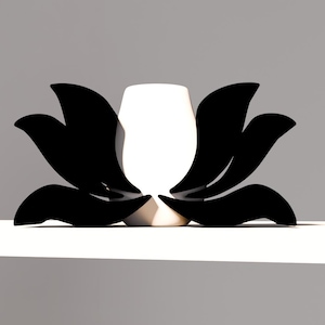 May include: A decorative lotus flower-shaped object with black petals and a white center. The object is set against a neutral gray background, creating a minimalist aesthetic. The design is modern and elegant.