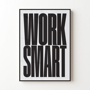Op de afbeelding: Een rechthoekige wandkunstprint met de dikgedrukte zwarte tekst WORK SMART in een hoog, schreefloos lettertype tegen een effen witte achtergrond. De print is ingelijst in een dunne zwarte lijst, wat zorgt voor een contrastrijk grafisch ontwerp.
