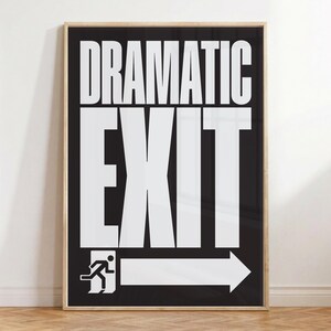 Peut inclure: Une affiche encadrée avec les mots "DRAMATIC EXIT" en grandes lettres majuscules blanches sur fond noir. Une flèche blanche et un pictogramme de sortie sont en bas. Le cadre est de couleur bois clair.