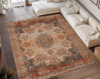 May include: A rectangular area rug with an ornate, vintage-inspired design. The rug features a beige central field with a detailed pattern in shades of blue, orange, and brown. The border is a darker shade of blue and orange.