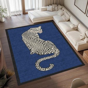 Peut inclure: Un tapis rectangulaire bleu avec une bordure noire présente une grande illustration d'un léopard. Le léopard est représenté en position assise, la tête tournée vers le spectateur. La fourrure du léopard est blanche avec des taches noires.