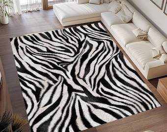 May include: A rectangular zebra-print rug with black and white stripes. The rug is placed on a wooden floor in a living room setting, with a white sectional sofa and natural light.