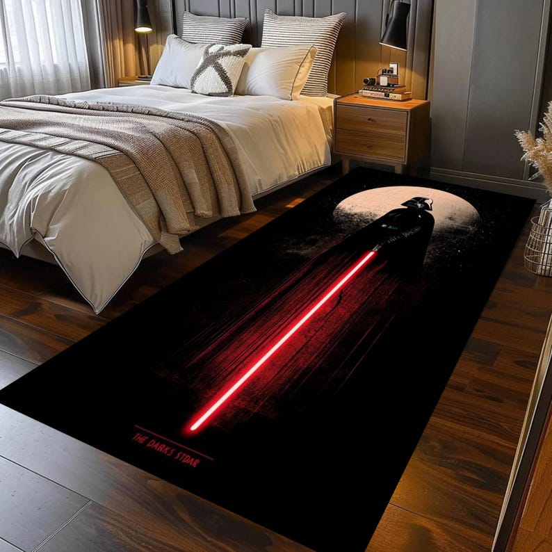 Puede incluir: Alfombra rectangular negra con un gr&aacute;fico de Darth Vader y un sable de luz rojo. Una gran luna blanca est&aacute; en el fondo. El texto "THE DARK SIDE" est&aacute; en la parte inferior.