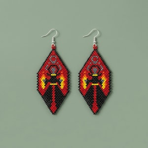 May include: A pair of beaded earrings with a diamond shape. The earrings feature a red background with black, yellow, and gray geometric patterns. The earrings have silver-colored fish hook ear wires.