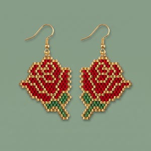 May include: A pair of dangle earrings featuring a rose motif crafted from small red, green, and metallic gold beads. The rose design is composed of a grid-like pattern of beads, suspended from gold-toned metal fishhook ear wires for pierced ears.