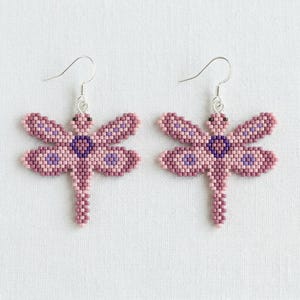 May include: A white ceramic mug with a black handle and the text "But First, Coffee" in a black, handwritten-style font. The mug is on a white surface.