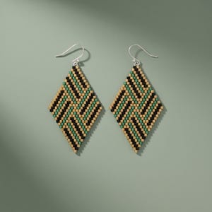 May include: A pair of diamond-shaped drop earrings crafted from small seed beads in a geometric pattern. The beads are arranged in alternating diagonal stripes of black, metallic gold, and forest green, suspended from silver-toned metal hooks.