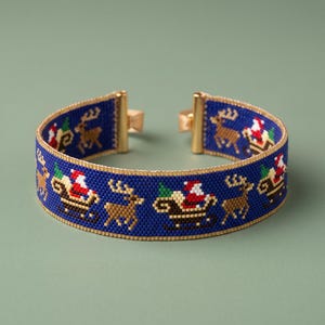 Puede incluir: Una pulsera de cuentas azul con un patrón repetitivo de Santa Claus en un trineo tirado por renos. El diseño incluye pequeños árboles verdes y está rematado con terminales de metal dorado y un borde fino de color dorado en los extremos.