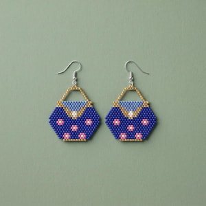 May include: A pair of beaded earrings in a purse design. The earrings are primarily navy blue with pink flower accents. The top of the purse is light blue and gold. The earrings hang from silver hooks.