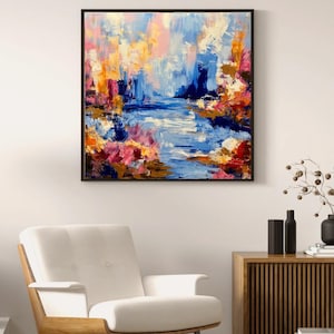 May include: Abstract landscape painting in a black frame. The artwork features a river scene with blue, pink, orange, and yellow brushstrokes. The painting hangs above a white armchair and a wooden cabinet.
