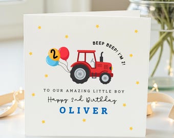 May include: A white square greeting card featuring a red tractor illustration pulling a blue, yellow, and red balloon cluster. The card includes the text BEEP BEEP! I'M 2!, TO OUR AMAZING LITTLE BOY, Happy 2nd Birthday, and the name OLIVER in blue.