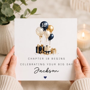 Puede incluir: Una tarjeta de felicitación cuadrada con un grupo de globos azul marino, dorados y blancos, uno marcado con el número 18, sobre dos cajas de regalo y un pastel pequeño. El texto dice: CHAPTER 18 BEGINS, CELEBRATING YOUR BIG DAY, Jackson, y un corazón.