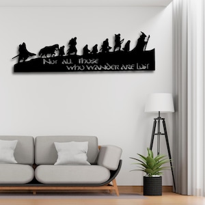 Può includere: Arte da parete in metallo nero con una silhouette di personaggi e la scritta "Not All Those Who Wander Are Lost". L'opera raffigura un gruppo di figure che camminano su un paesaggio, ideale per l'arredamento della casa.