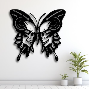 Puede incluir: Decoración de pared de metal negro con forma de mariposa con un diseño único. Las alas y el cuerpo de la mariposa están detallados con motivos de calaveras y huesos. La obra de arte está montada en una pared blanca, creando un fuerte contraste. Ideal para un toque gótico.