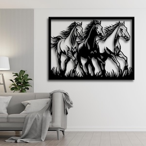 May include: Black framed wall art featuring three running horses. The horses are depicted in a stylized, cut-out design, with flowing manes and tails. The artwork is set against a white background, with grass at the bottom.