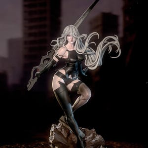 May include: A detailed figurine of a female character with long, flowing white hair, clad in a black bodysuit and leggings. She holds a large, ornate sword. The figure is posed on a rocky base, with a blurred cityscape in the background.