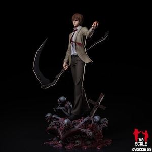 Op de afbeelding: Gedetailleerd beeldje van een personage uit de anime-serie Death Note. Het beeldje draagt een beige blazer, houdt een zeis en een appel vast. De basis heeft schedels, een grafsteen en een kruis. Het beeldje is 1/8 schaal.