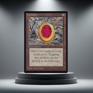 Può includere: Una carta di Magic: The Gathering, "Mox Ruby", con un ciondolo d'oro con una grande gemma rossa. Il testo della carta recita "Aggiungi 1 mana rosso al tuo mana pool." L'illustrazione è di Dan Frazier.