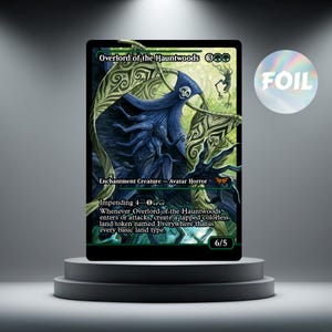 Op de afbeelding: Een Magic: The Gathering-kaart met de "Overlord of the Hauntwoods". De kaart heeft een gedetailleerde illustratie van een spookfiguur met blauwe en groene accenten. Het woord "FOIL" is zichtbaar aan de rechterkant.