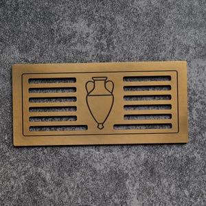 May include: A rectangular, bronze-colored vent cover with horizontal slits and a central outline of an amphora. The vent cover is made of metal and has a matte finish. The design is simple and elegant, suitable for various interior styles.