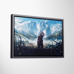 May include: A rectangular framed wall art print featuring a landscape illustration of a figure standing in a field, facing snow-capped mountains under a bright blue sky. The figure carries two swords on their back, with birds flying overhead.