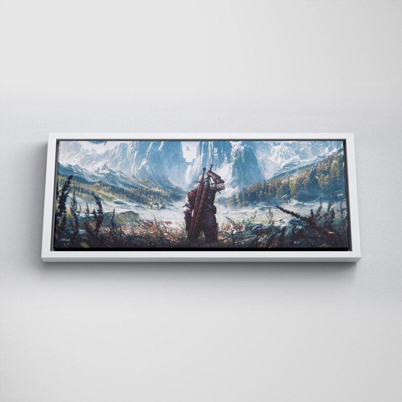 May include: A rectangular canvas wall art print featuring a landscape illustration of a figure standing in a field, carrying a sword on their back, facing snow-capped mountains and a forest under a bright sky, framed in a simple white border.