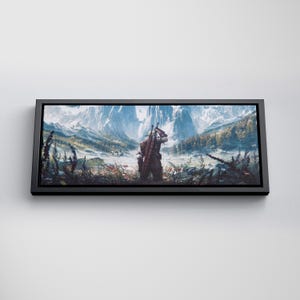 May include: A rectangular wall art print in a black frame featuring a landscape illustration of a figure standing in a field, carrying a sword on their back, facing snow-capped mountains and a forest under a bright, clear sky.