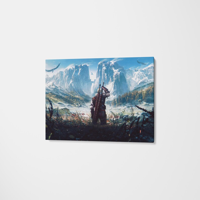 May include: A rectangular canvas wall art print featuring a fantasy landscape with a central figure seen from behind, carrying two swords on their back. The scene depicts snow-capped mountains, a lush valley, and flying birds under a bright blue sky.