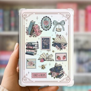 Peut inclure: Une coque de tablette transparente avec un motif fantaisiste de livres, de fleurs, de timbres et d'un nœud. Le design comprend le texte "STORIES & DREAMS" dans une bannière rose. La coque est tenue dans une main, avec un arrière-plan flou d'étagères.