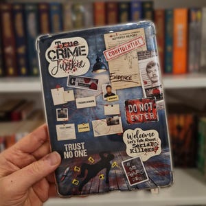Peut inclure: Une coque de tablette transparente avec un design de collage sur le thème des crimes réels. Le graphique inclut des textes comme True Crime Junkie, Confidential, Do Not Enter, Trust No One et Welcome Let's Talk About Serial Killers, avec des rapports d'autopsie, des étiquettes de preuves et une silhouette de corps sur un plancher en bois.