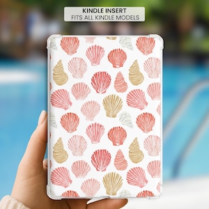 May include: A clear Kindle insert featuring a repeating pattern of watercolor-style seashells in shades of coral, pink, and tan on a white background. The text at the top reads: KINDLE INSERT FITS ALL KINDLE MODELS. The design covers the entire surface.
