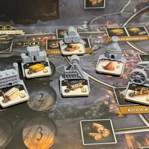 Puede incluir: Un juego de mesa con miniaturas grises de estructuras como edificios y maquinaria sobre cartas. El tablero es un mapa con nombres de ciudades e ilustraciones, con una estética oscura y envejecida.