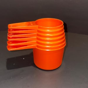Juego de vasos medidores apilables Tupperware de color naranja, estilo vintage.