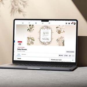 May include: A laptop displays a baby shower invitation. The invitation features floral and botanical illustrations with the text "Baby Shower Shelly." The laptop is open on a light-colored surface.