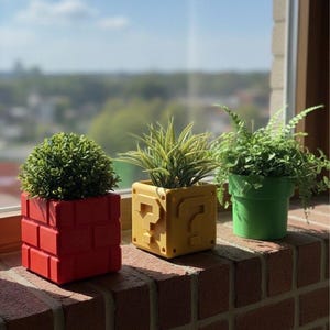 Puede incluir: Tres macetas decorativas sobre una repisa de ladrillo. Una maceta roja con forma de ladrillo contiene una planta verde. Una maceta amarilla con forma de bloque de interrogación contiene una planta espinosa. Una maceta verde contiene un helecho.