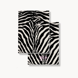 May include: Two rectangular notebooks featuring a bold black and off-white zebra stripe pattern. The bottom notebook displays the text DES and ARSENE CO in a light pink gothic-style font centered near the bottom edge of the cover design.
