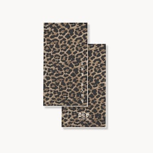Peut inclure: Deux cartes rectangulaires avec un motif imprimé léopard marron et noir. La carte de gauche affiche le texte vertical CRY BABY dans une police gothique blanche. La carte de droite présente le texte DES ABLENE VO en police gothique blanche.