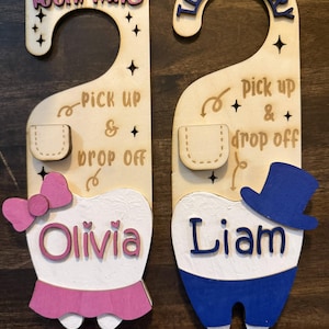 Könnte beinhalten: Zwei Türschilder aus Holz für die Zahnfee. Eines ist rosa und weiß mit dem Namen "Olivia", das andere ist blau und weiß mit dem Namen "Liam". Beide haben Taschen und lesen "Pick up & drop off".